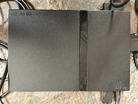 Top view of the black Sony PlayStation 2 Slim console, showing matte and gloss surfaces, and Sony branding.