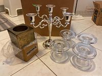 Set of candle holders showing metal candelabra, glass holders, and square metal holder in box plastic wrap.