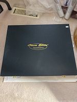 Closed black box packaging with gold Casa Elite Home Collection logo, lying flat on floor.