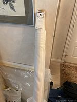 Full view of the fabric bolt standing upright showing the rolled fabric and label on top