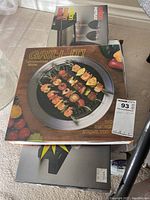 Box of Salton indoor smokeless stovetop grill showing skewered grilled food on cover.