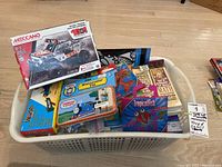 Full lot view showing Meccano set, Thomas the Tank Engine watercolour set, Brain Quest cards, Tropical Fish kit, and other craft and educational kits in a basket