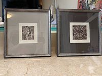 Photo showing two framed black and white prints side by side on a table surface