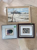 Original oil painting of a snowy landscape with tree, and two smaller framed prints nearby on the floor.