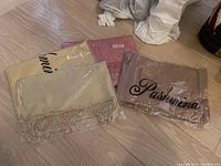 Four silk blend pashminas new in packaging, with visible color variations and printed 'Pashmina' branding.