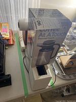 White vacuum sealer with a roll of vacuum bags and boxed thermal carafe on top