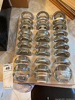 Thirty clear glass tea light holders neatly arranged in original packaging.