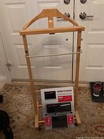 Wooden valet stand with Swiss Gear wallet in original packaging displayed on the lower shelf.