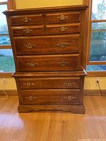 Front view of the Huffman Koos armoire showing five drawers with brass handles and detailed molding.