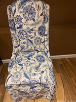 Front view of the blue and white upholstered lady's chair showing floral patterned fabric and skirted base.