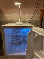 Open Avanti mini fridge with blue interior light and shelving