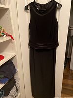 Front view of sleeveless black dress showing satin trim at neckline and waist.