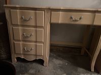 Front view of desk showing three deep drawers on left and one long drawer above kneehole with metal handles. Details of carved wood edges visible.