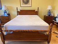 Front view of the queen bed showing headboard, footboard, and mattress on wooden frame