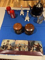 Kitchen items arranged on blue cloth showing salt and pepper shakers, coaster set, teapot with brewing basket