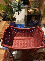 Photo showing the lacquer chest with floral handpaint, the maroon woven basket, and the potted plant on a table.