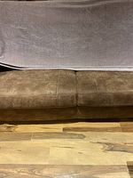 Full view of the folded lilac blanket showing texture and color on a brown couch.