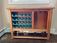 Front view of wooden wine bar showing turquoise wine bottle rack on left and open storage on right with brass petroglyph decorations at bottom front panel.