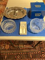 All four items displayed on blue table: Kosta Boda bowl with box, Gorham bowl, Mikasa stopper in box, Gorham serving platter.