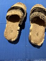 Top view of UGG slippers showing fluffy footbed and strap with buckle