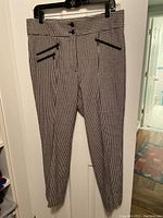 Front view of black and white check pants showing high waist with two buttons and three slanted zippered pockets