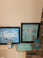 Set of items including two framed wooden prints (crab and mermaid), Carpe Diem wooden sign, unopened candle jar, and blue glass tea candle hurricane lantern.