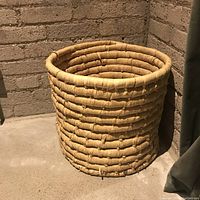 Side view of large round woven basket showing texture and some wear.