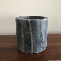 Front view of the cylindrical dark marble planter with visible natural veining and scratches.