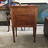 Full front view of one nightstand showing three drawers and tapered legs
