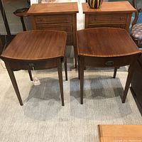 Pair of antique wooden side tables shown front view with drawer and extensions closed.