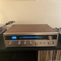 Front view of Pioneer receiver showing blue-lit tuner with analog scale and control knobs on metal faceplate with woodgrain casing.