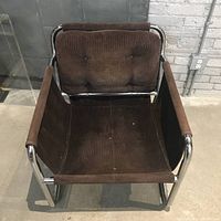 Front view of vintage mid-century modern chrome frame lounge chair. Shows tufted brown corduroy back cushion and missing bottom cushion with sling seat fabric.