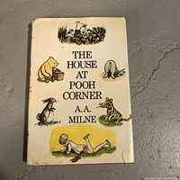Front cover of vintage hardcover book with illustrated dust jacket titled "The House at Pooh Corner" by A.A. Milne.