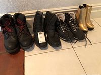 All four pairs of boots lined up on the floor (Madden, Timberland, women's athletic boots, gold rubber sole boots)