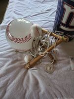 Hanging baseball-themed chandelier with multiple baseball-shaped lights and wooden bat elements, wires tangled.