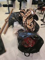 Bags containing silk drapes in floral and checkered patterns, partially visible inside black plastic bags.