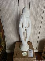 Front view of the 20 inch white Haeger statue against a wood panel background, highlighting its abstract form and matte finish.