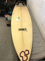Full length view of white Al Merrick surfboard showing its overall shape and wear