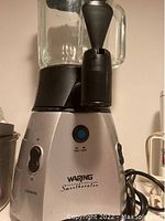 Front view of Waring SmoothERATOR smoothie maker and dispenser, showing controls and glass jar with spout.