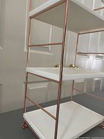 Close-up side angle of the 3-tier bathroom organizer showing white shelves and rose gold metal frame