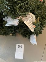 Close-up showing green electrical plug, part of the pre-lit garland and attached product tags.