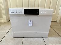 Front view of the white Comfee countertop dishwasher with control buttons and digital display.