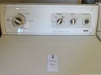 Close-up photo of control panel showing cycle options, fabric care, and start button, white color.