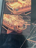 Close-up photo showing detailed rear and side view of the wooden model ship, highlighting cabin, railings, rigging, and curved stern features.