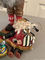 Close-up of fabric Santa figurine sitting with plaid patchwork clothing, lace collar, and sack bag