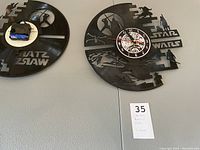 Photo showing the back of one vinyl record clock with visible clock mechanism attached and partial Star Wars logo cutout.