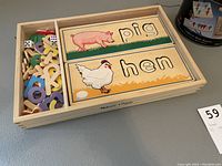 Wooden letter puzzle board featuring pig and hen pictures with colorful alphabet letters in a wooden tray.