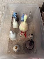 Top view of the assortment of nine decorative bells in a plastic bin on carpet