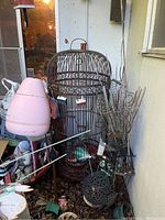 Photo of large tall metal birdhouse with domed top and vertical bars. Surrounded by various outdoor items and garden accessories.