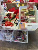 Bin with assorted Christmas-themed stuffed animals, fabric napkins, and holiday decor items.